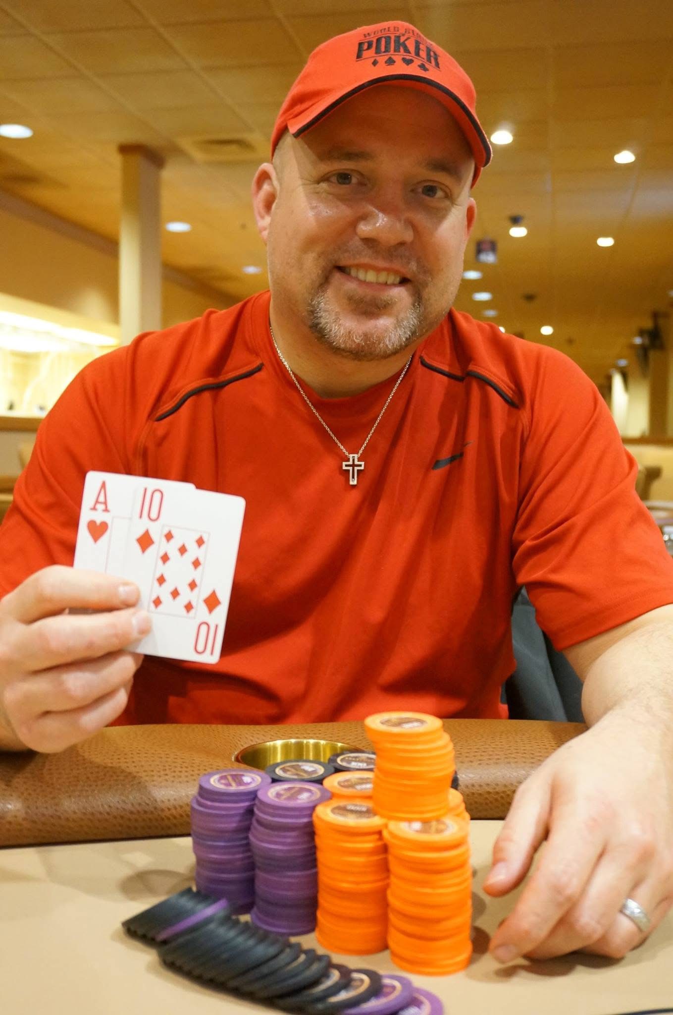 Lee Childs smiling at the poker table, holding ace ten