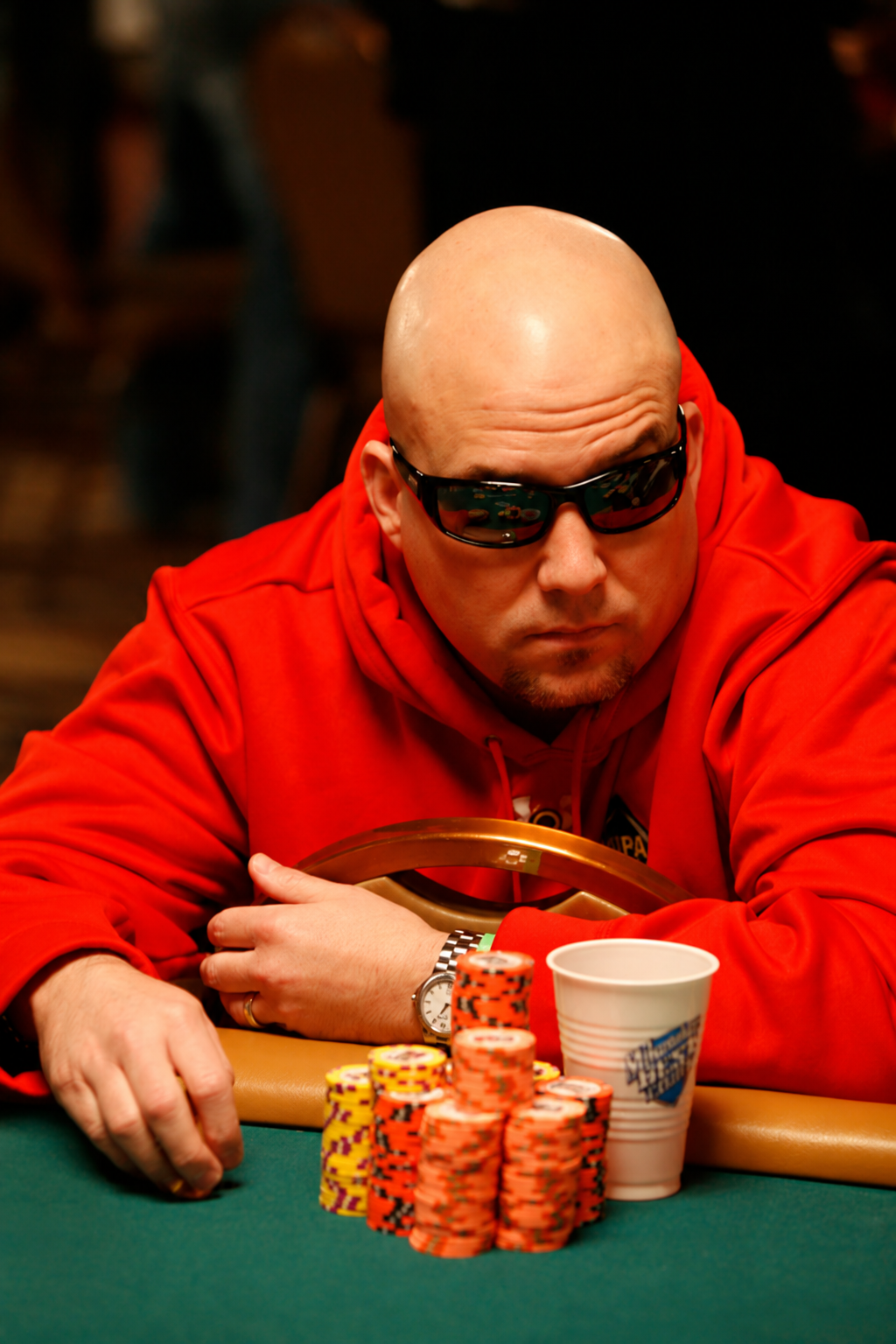 Lee Childs in his signature red hoodie and sunglasses at the poker table